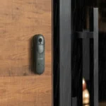 Sonnette vidéo Reolink Doorbell Battery fixée sur un cadre de porte en bois sombre