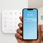 Main tenant un smartphone avec une notification Ring devant le clavier blanc du kit Ring Alarm Kit M